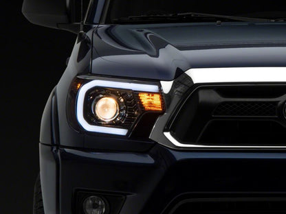 Raxiom 12-15 Toyota Tacoma Axial Projector Headlights w/ SEQL LED Bar- Black Housing (Clear Lens)